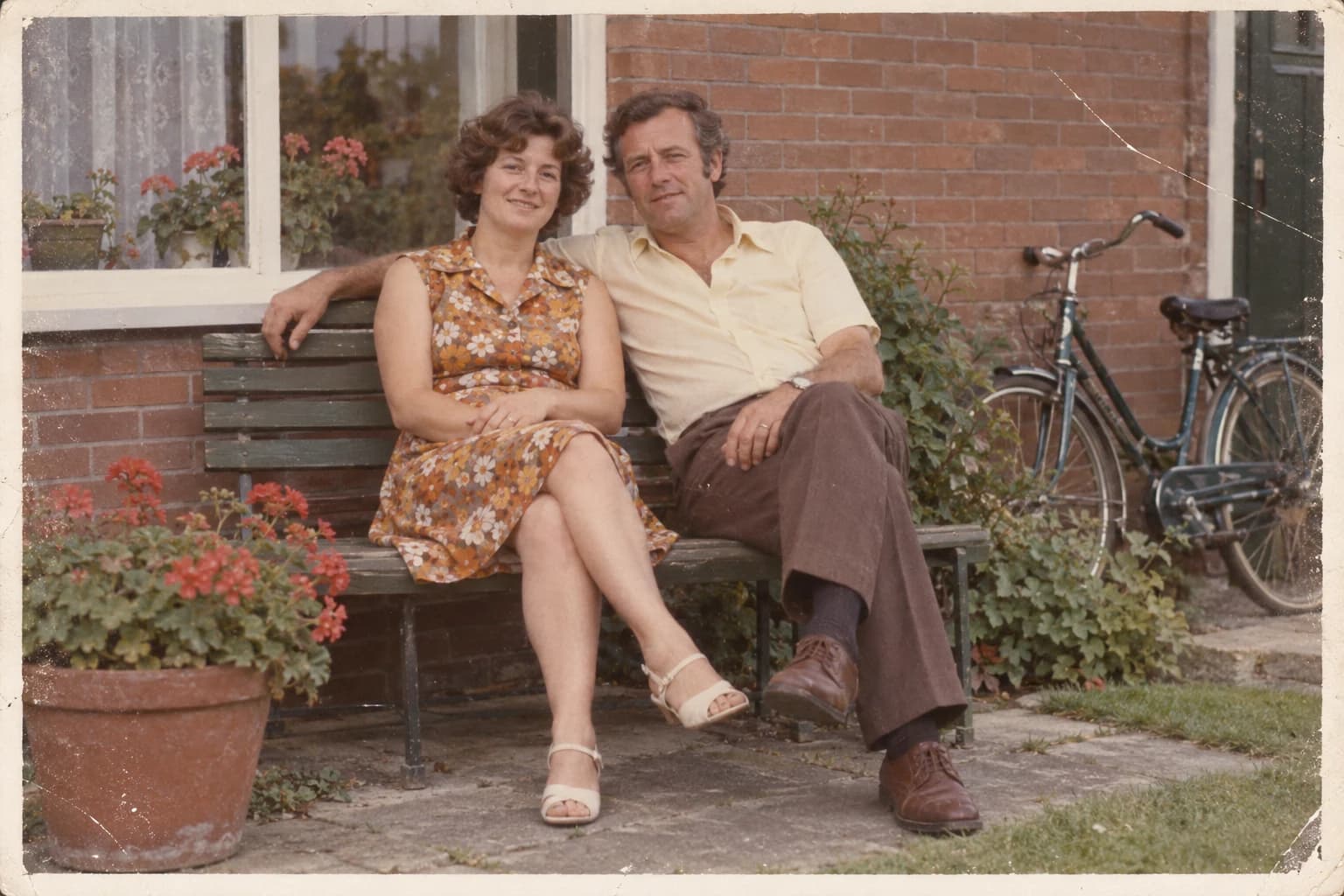 Synthetic faded snapshot of two fictional adults on a garden bench, with scratches and a worn print border.